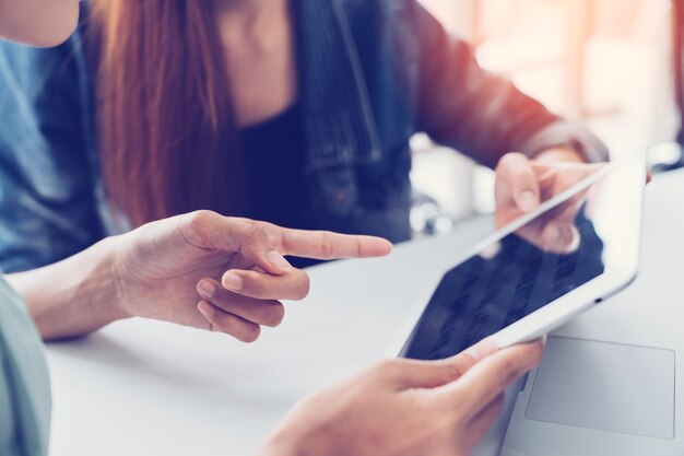 Mani tagliate di una donna d'affari che discute con una collega su un tablet digitale in ufficio