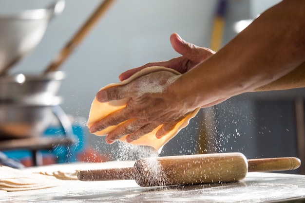 Mani tagliate di una persona che fa chapatti in cucina a casa