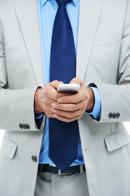 Mani telefono e uomo d'affari in studio per la ricerca della comunicazione e la digitazione di un messaggio Closeup professionale e internet o voip per la conversazione online e-mail e app su sfondo bianco