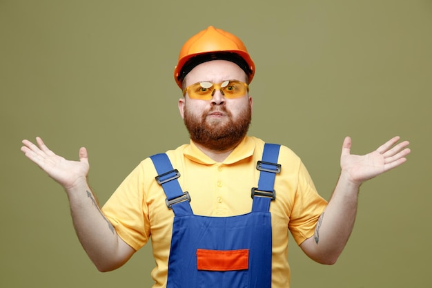 Mani tese che si allargano giovane costruttore in uniforme isolato su sfondo verde 2