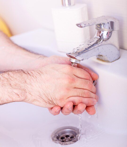 Mani umane lavate sotto un flusso di acqua pura