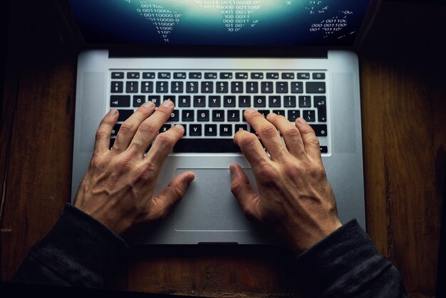 Mani uomo e portatile per l'hacking di notte software di database e hacker per l'attacco informatico programmazione tastiera malware e spam sistema o algoritmo per phishing ladro e script di codifica sopra