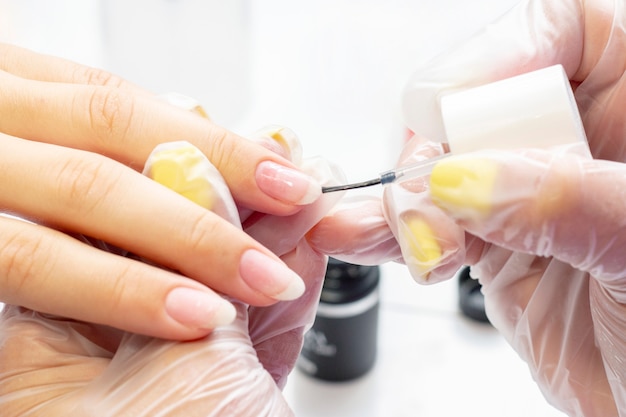 Manicure applica la base al cliente sotto gel smalto