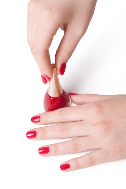 Manicure che applica smalto rosso sulle dita femminili