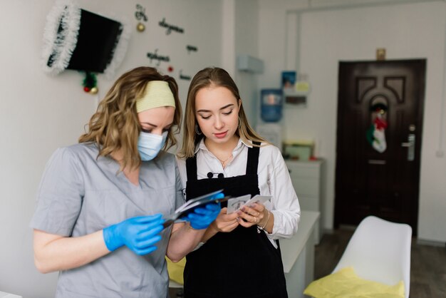 Manicure che indossa una maschera protettiva che dipinge unghie femminili con smalto per unghie in un salone di manicure.