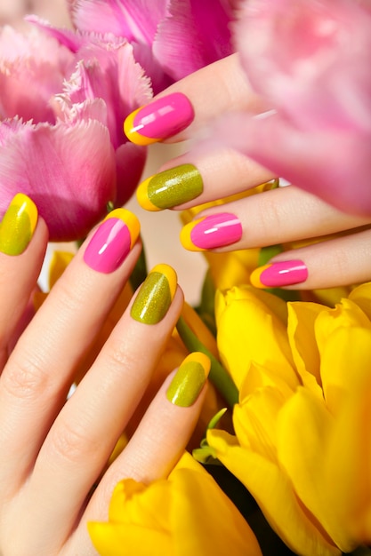 Manicure francese verde giallo con smalto rosa e primo piano dei tulipani