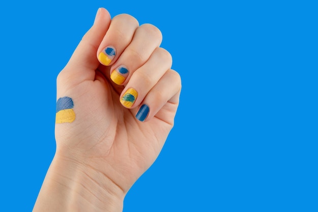 Manicure gialla e blu sullo sfondo della bandiera ucraina