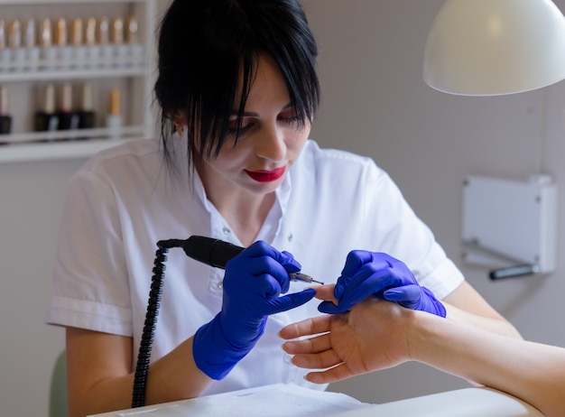 Manicure master usando una macchina per pulire le unghie