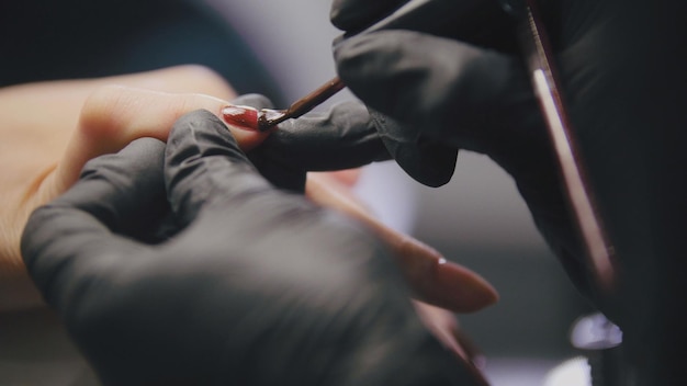 Manicure nel salone di bellezza - il maestro cosmetico in maschera medica si occupa di lucidare le unghie, primo piano