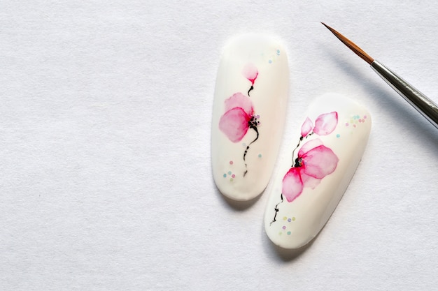 Manicure primaverile. Suggerimenti con il disegno di fiori di primavera su un muro bianco