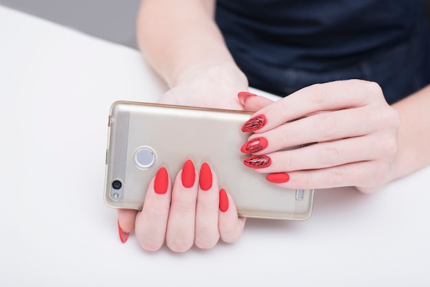 Manicure rossa. Smart phone in mano femminile.