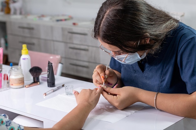 Manicurista professionista che applica il gel alle unghie di una donna Unghie da salone in un salone di bellezza