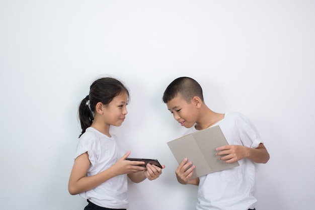 Manifestazione della bambina qualcosa in smartphone mentre libro della tenuta del ragazzino