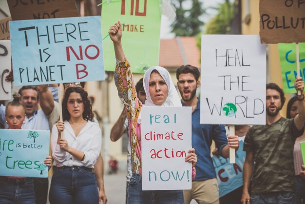 Manifestazione pubblica sulla strada contro il riscaldamento globale e l'inquinamento. Gruppo di persone multietniche che protestano per i cambiamenti climatici e i problemi di plastica negli oceani