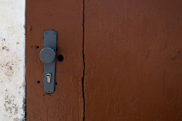 Maniglia della porta verniciata e buco della serratura di una porta della stalla marrone. Spazio vuoto