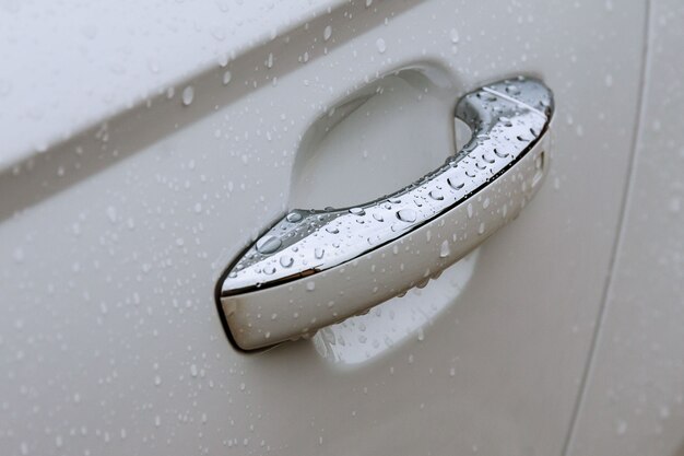 Maniglia della portiera dell'auto con il primo piano delle gocce di pioggia.