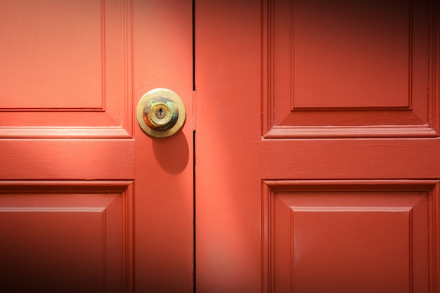 Maniglie delle porte in ottone alla porta di legno rosso