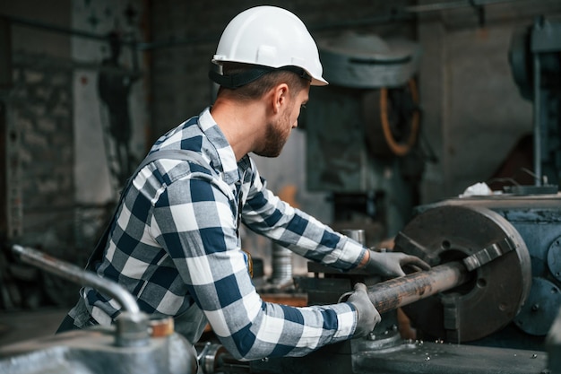 Manipolazione della macchina industriale Il lavoratore di fabbrica in uniforme è al chiuso