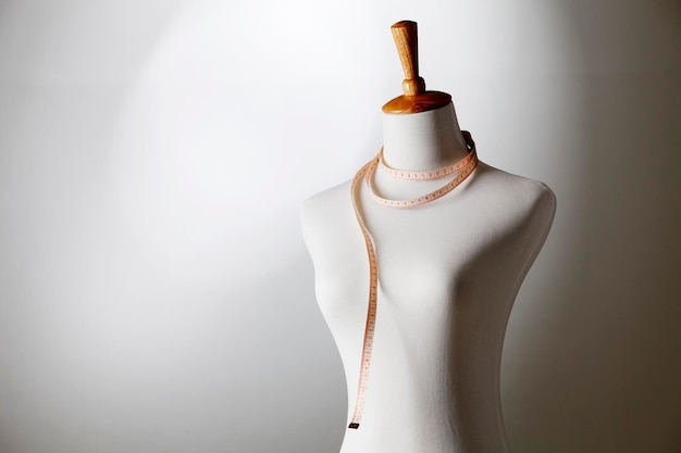 Mannequin with tape measure against wall