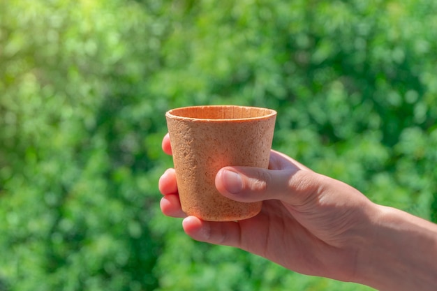 Mano azienda commestibile waffle tazza di caffè su sfondo verde zero rifiuti concept