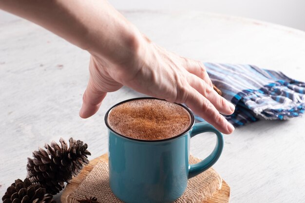 Mano che afferra la tazza blu con la bevanda calda