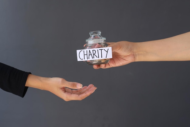 Mano che dà salvadanaio a portata di mano su sfondo grigio. Sfondo di donazione e beneficenza.