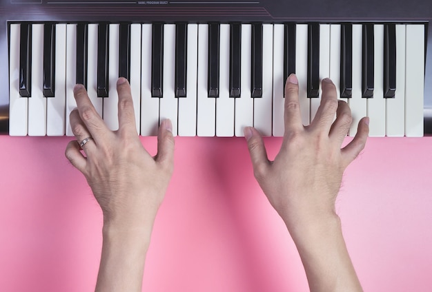 Mano che gioca la tastiera musicale su sfondo rosa