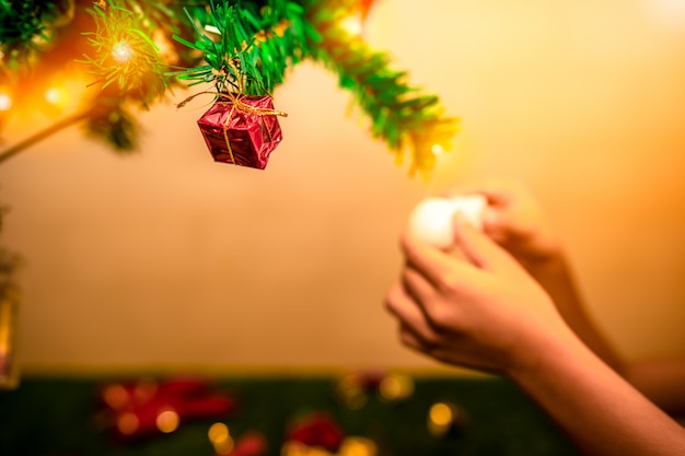 Mano che mette il contenitore di regalo sull'albero di Natale