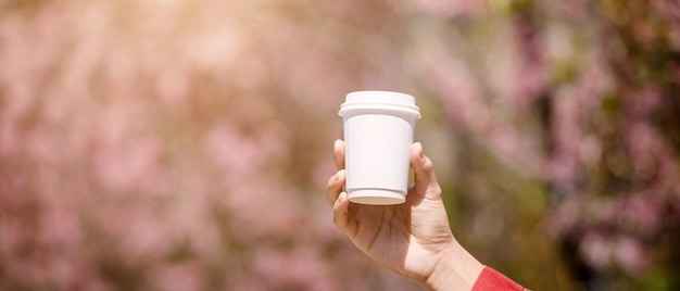 Mano che mostra una tazza bianca di caffè caldo