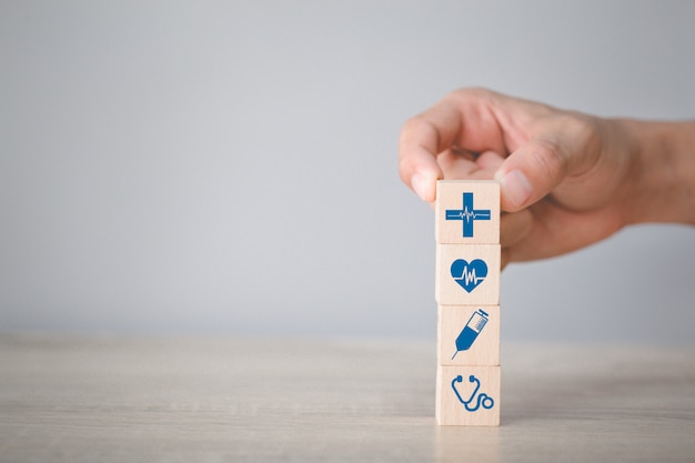 Mano che organizza i blocchi di legno che impilano con le icone mediche e di sanità