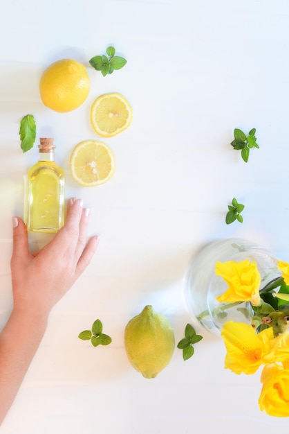 Mano che prepara una sana bevanda fresca, limone, menta e acqua. Mano che tiene l'olio di limone Bevanda salutare