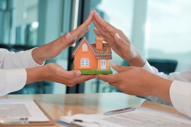 Mano che protegge il modello di casa. assicurazione sulla casa, sicurezza.