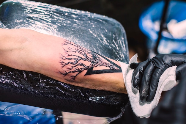 Mano che pulisce il tatuaggio fresco sul braccio