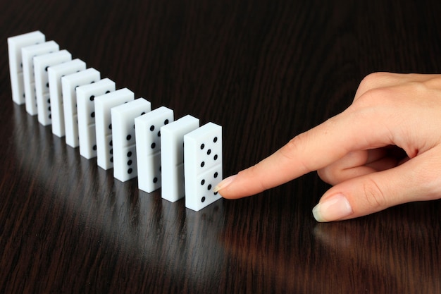 Mano che spinge i domino su fondo di legno