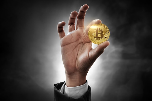 Mano che tiene bitcoin d'oro