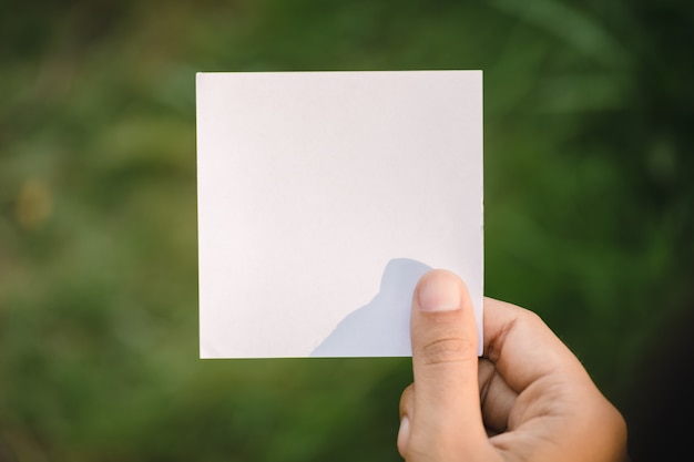 Mano che tiene carta in bianco sulla natura