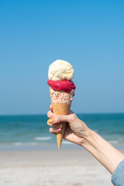 mano che tiene cono gelato con sfondo azzurro del cielo e spazio copia