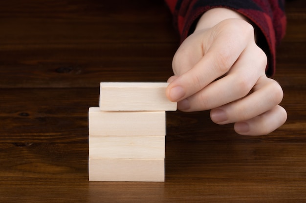 Mano che tiene il cubo di legno con il blocco ribaltabile sullo sfondo del tavolo