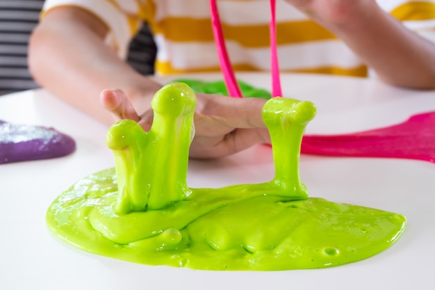 Mano che tiene il giocattolo chiamato Slime, fratello e sorella di Sibling divertendosi ed essendo creativi