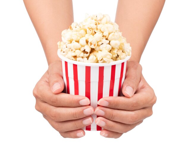 Mano che tiene il popcorn nel secchio a strisce isolato su sfondo bianco