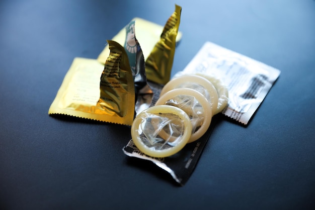Mano che tiene il preservativo con l'HIV e gli involucri del sesso sicuro sullo sfondo Promuovere il sesso sicuro e la protezione