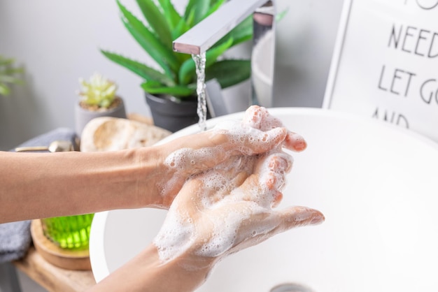 Mano che tiene il sapone vicino al lavandino con acqua