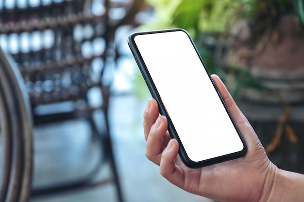 mano che tiene il telefono cellulare nero con schermo bianco vuoto in esterno