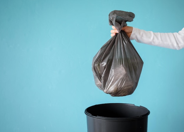 Mano che tiene immondizia in un sacchetto di plastica