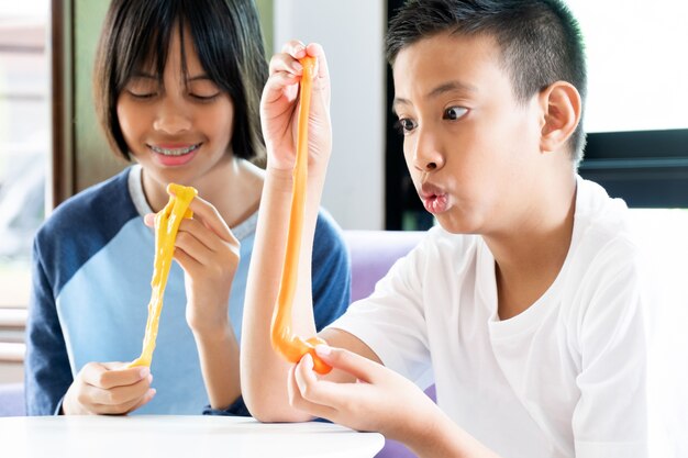 Mano che tiene in casa Toy Called Slime, ragazzo e ragazza del fratello germano divertendosi ed essendo creativo dall'esperimento di scienza.