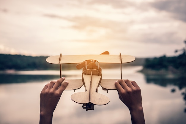 Mano che tiene l'aeroplano di legno nel natur