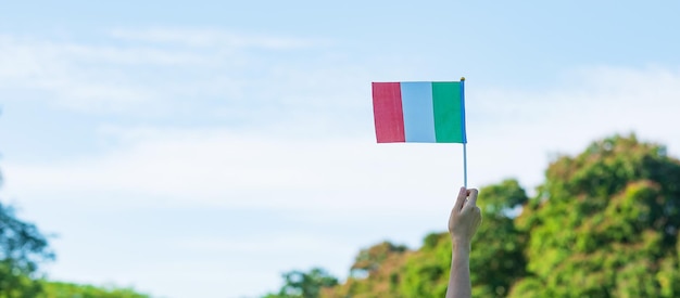 Mano che tiene la bandiera dell'Italia sullo sfondo della natura Festa nazionale Festa della Repubblica Festa della Repubblica e concetti di celebrazione felice