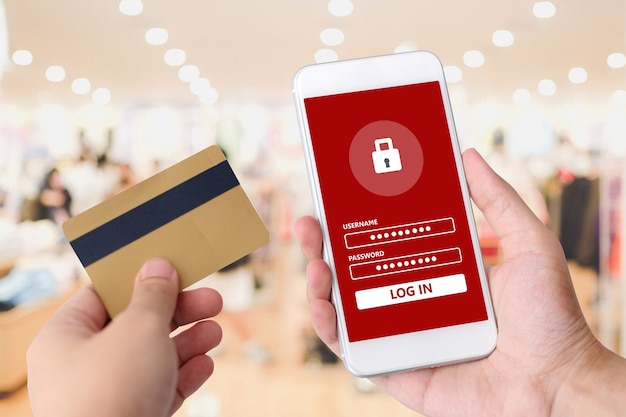 Mano che tiene la carta di credito e smart phone con password accedere sullo schermo per lo shopping onlin