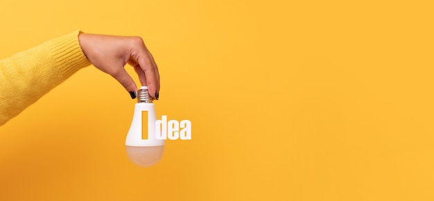 Mano che tiene la lampadina con idea di iscrizione, mock-up panoramico