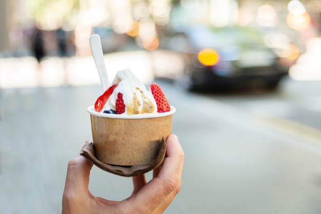 Mano che tiene la tazza di carta con gelato